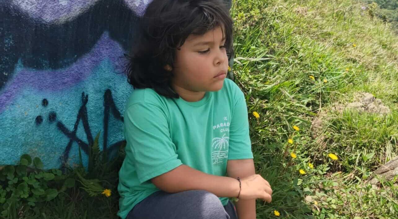 Adrián sentado en la montaña mirando hacia la ciudad